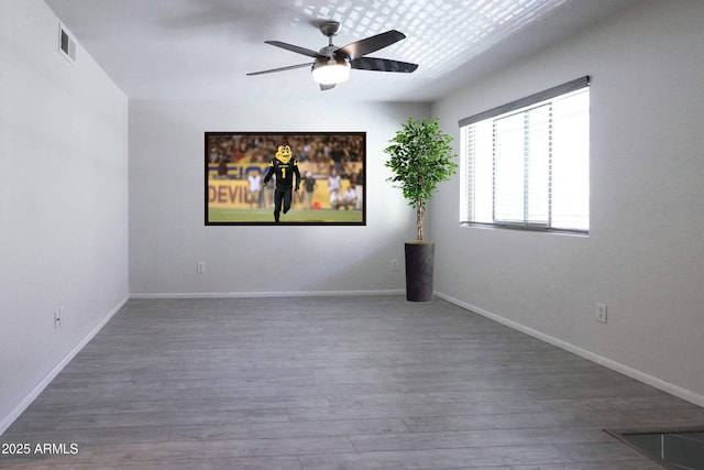 empty room featuring ceiling fan, wood finished floors, visible vents, and baseboards