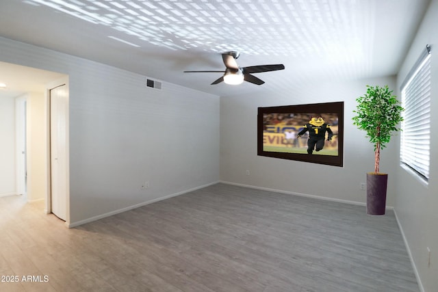 empty room featuring light wood-type flooring, visible vents, baseboards, and a ceiling fan