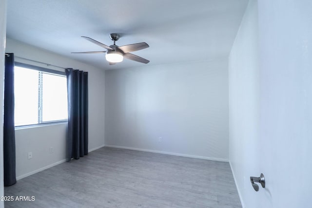 empty room with ceiling fan, baseboards, and wood finished floors