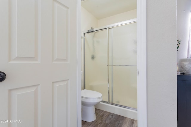 bathroom with toilet, hardwood / wood-style flooring, and an enclosed shower