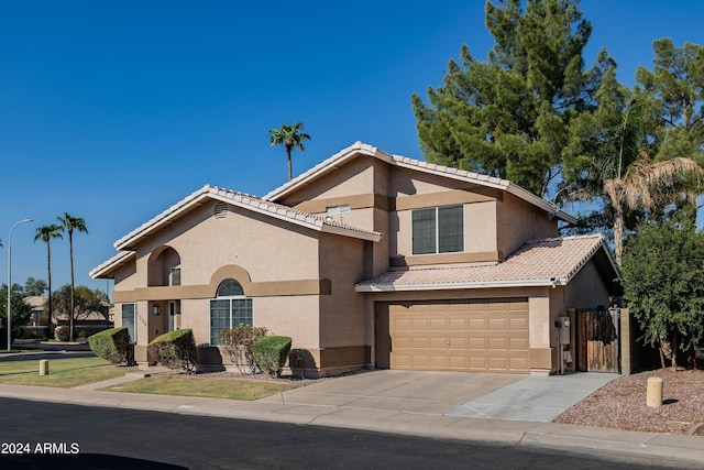 traditional-style home featuring stucco siding, driveway, a gate, an attached garage, and a tiled roof