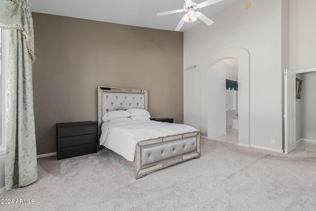 bedroom featuring light carpet, ensuite bath, ceiling fan, and high vaulted ceiling