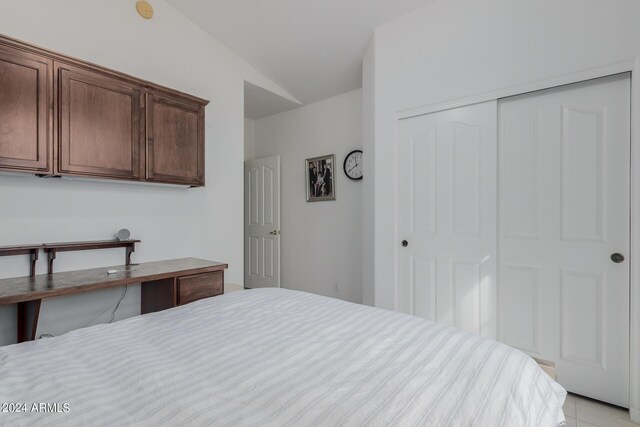 tiled bedroom featuring vaulted ceiling and a closet