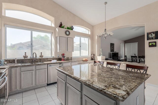 kitchen with lofted ceiling, a kitchen island, decorative light fixtures, appliances with stainless steel finishes, and an inviting chandelier