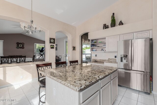 kitchen featuring lofted ceiling, hanging light fixtures, stainless steel fridge with ice dispenser, a kitchen breakfast bar, and a center island