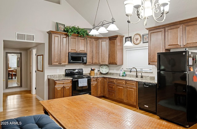 kitchen with light stone countertops, a chandelier, pendant lighting, black appliances, and sink