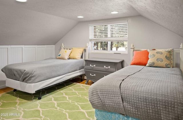 bedroom with lofted ceiling, hardwood / wood-style flooring, and a textured ceiling