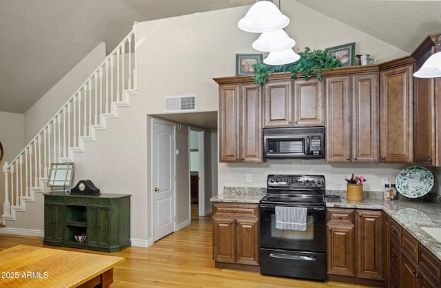 kitchen with light stone countertops, vaulted ceiling, hanging light fixtures, light hardwood / wood-style floors, and black appliances