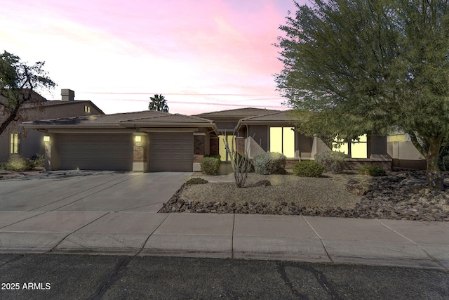 view of front of property featuring an attached garage, a tiled roof, concrete driveway, and stucco siding