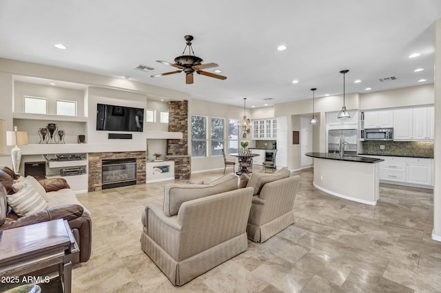 living area featuring recessed lighting, visible vents, and a stone fireplace