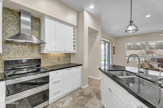 kitchen with a sink, white cabinetry, double oven range, wall chimney range hood, and decorative backsplash