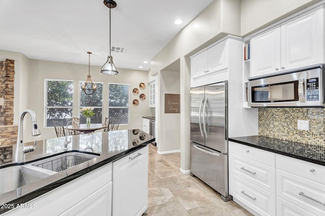 kitchen featuring tasteful backsplash, visible vents, white cabinets, stainless steel appliances, and a sink