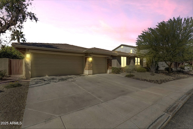 view of front of house featuring an attached garage, a tile roof, concrete driveway, and stucco siding