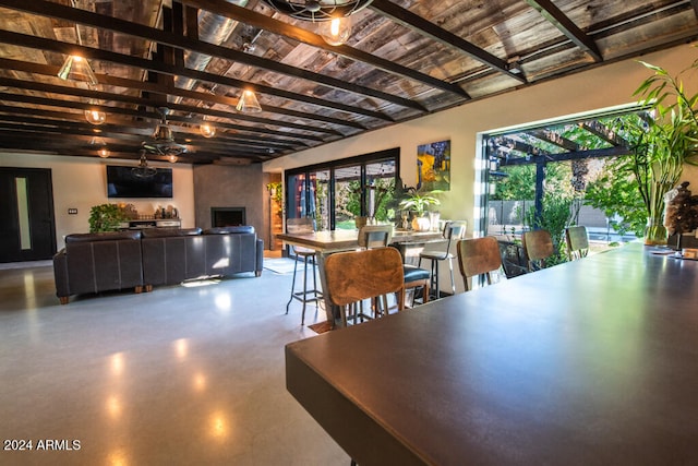 dining room featuring beamed ceiling, concrete flooring, and ceiling fan