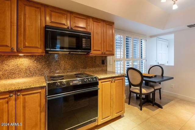 kitchen with light stone counters, light tile patterned flooring, tasteful backsplash, and black appliances