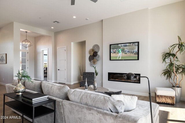 living room with ceiling fan with notable chandelier and dark hardwood / wood-style flooring