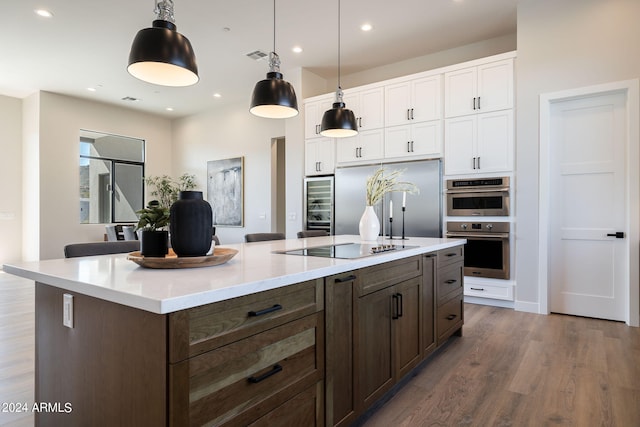 kitchen featuring white cabinetry, hardwood / wood-style floors, decorative light fixtures, a kitchen island, and appliances with stainless steel finishes