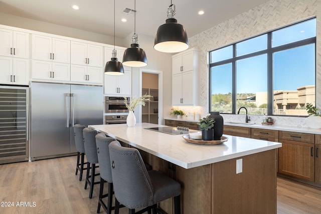 kitchen featuring pendant lighting, a center island, sink, white cabinetry, and stainless steel appliances