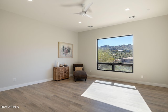 living area with hardwood / wood-style flooring, a mountain view, and ceiling fan