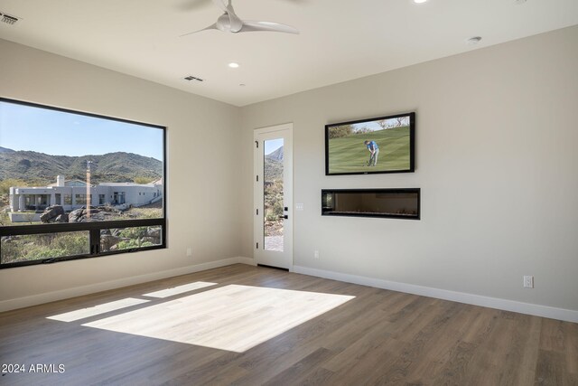 spare room featuring a mountain view, hardwood / wood-style floors, a wealth of natural light, and ceiling fan