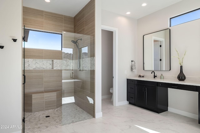 bathroom with a tile shower, vanity, and toilet