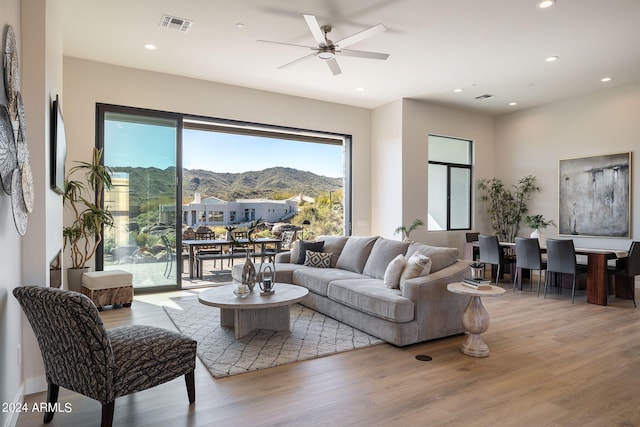 living room featuring a mountain view, light wood-type flooring, and ceiling fan