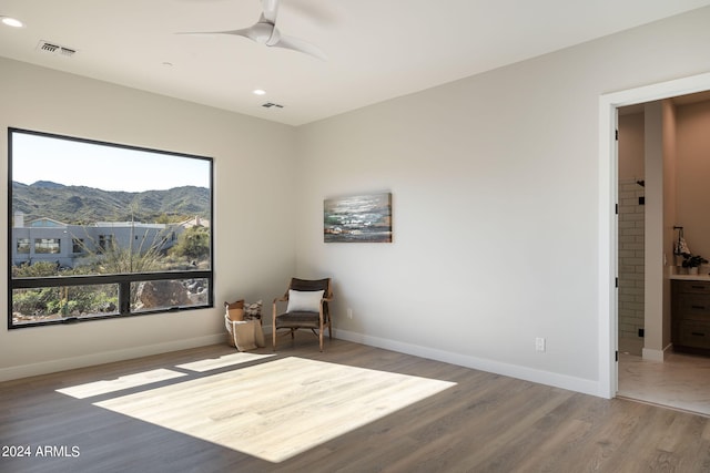 sitting room featuring hardwood / wood-style floors, a mountain view, and ceiling fan