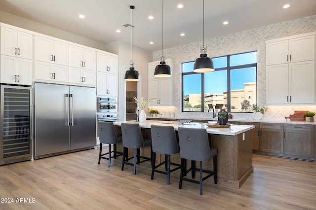 kitchen with a center island, stainless steel appliances, white cabinetry, and beverage cooler