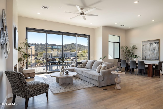 living room featuring a mountain view, hardwood / wood-style flooring, and ceiling fan