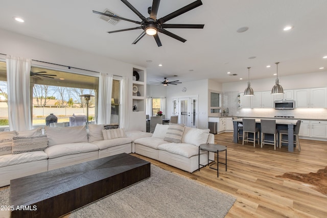 living room with visible vents, a ceiling fan, light wood-style flooring, and recessed lighting