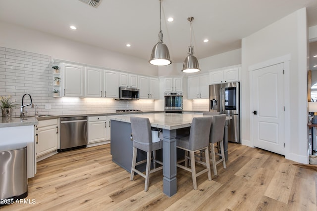 kitchen featuring stainless steel appliances, a kitchen island, open shelves, and white cabinets