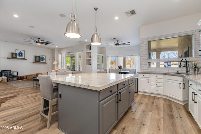 kitchen featuring open floor plan, a center island, gray cabinetry, white cabinetry, and a sink