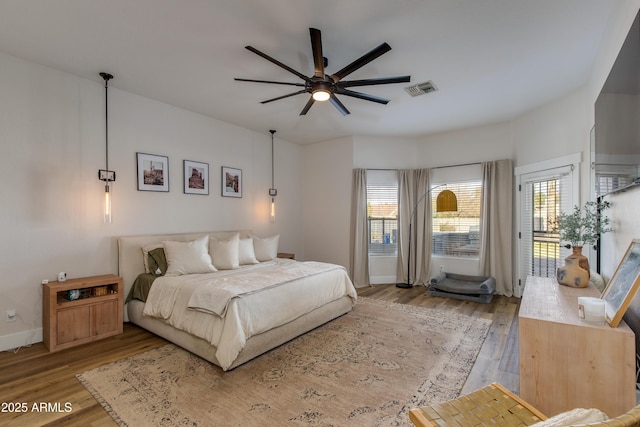 bedroom with access to outside, visible vents, baseboards, and wood finished floors