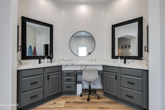 bathroom with double vanity, wood finished floors, and a sink