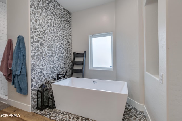 bathroom featuring a freestanding tub, baseboards, and wood finished floors