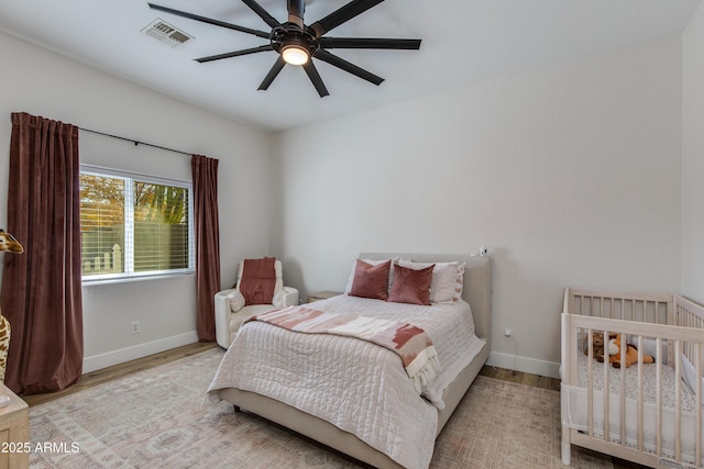 bedroom with light wood-type flooring, visible vents, ceiling fan, and baseboards