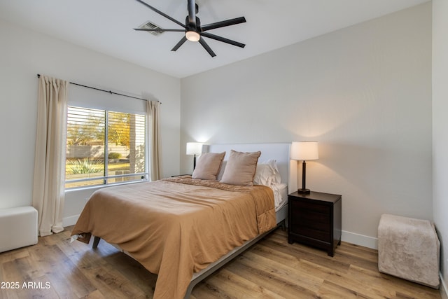 bedroom featuring light wood finished floors, baseboards, visible vents, and a ceiling fan