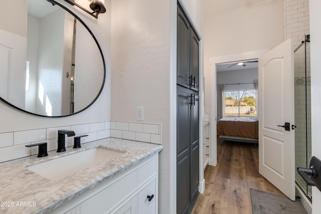 ensuite bathroom with ensuite bathroom, tasteful backsplash, wood finished floors, and vanity