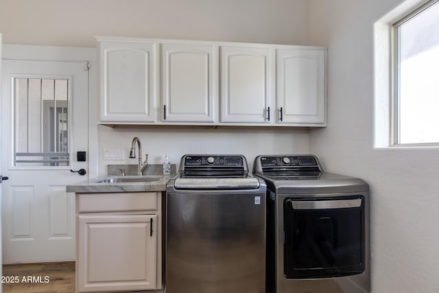 washroom with cabinet space, washer and clothes dryer, a sink, and wood finished floors