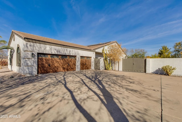 view of home's exterior featuring a gate, concrete driveway, and stucco siding