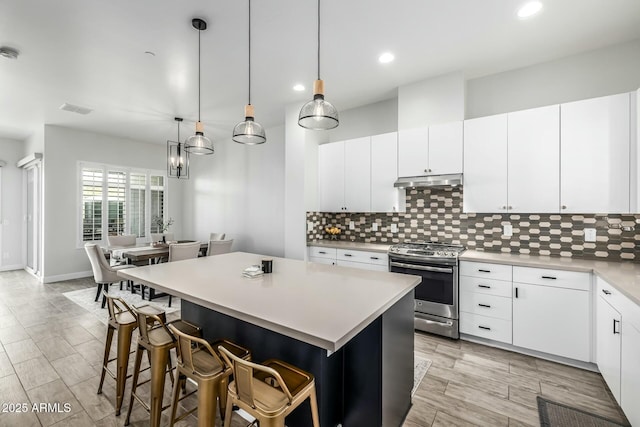 kitchen featuring white cabinetry, decorative backsplash, stainless steel range oven, and a kitchen island