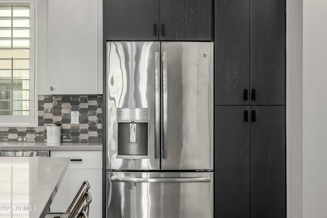 kitchen featuring white cabinets, stainless steel fridge, and backsplash