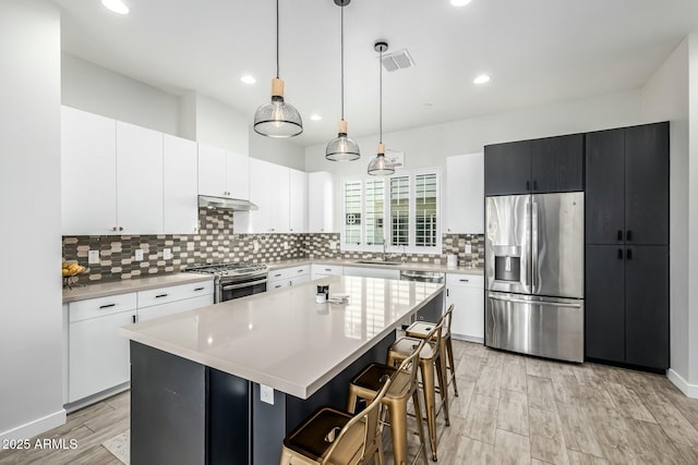 kitchen featuring sink, a center island, hanging light fixtures, appliances with stainless steel finishes, and white cabinets