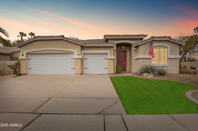 view of front of house with stucco siding, driveway, an attached garage, and a tiled roof