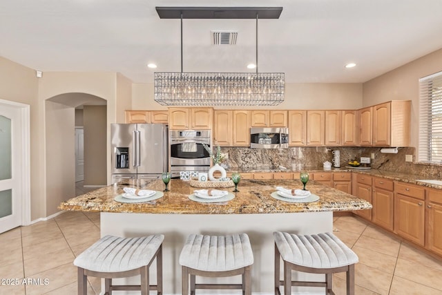 kitchen featuring light tile patterned floors, visible vents, arched walkways, and stainless steel appliances