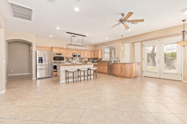 kitchen with visible vents, light brown cabinets, ceiling fan, arched walkways, and stainless steel appliances