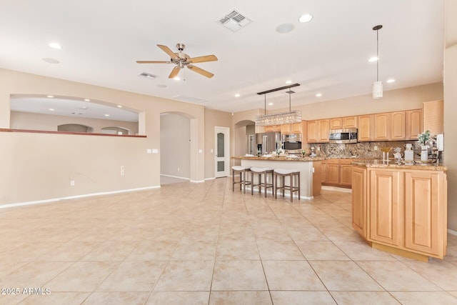 kitchen with a ceiling fan, visible vents, light brown cabinetry, and stainless steel appliances