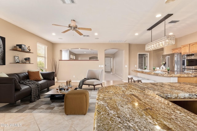 living area featuring a ceiling fan, recessed lighting, arched walkways, and visible vents