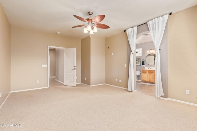 unfurnished bedroom featuring baseboards, light carpet, and ensuite bathroom