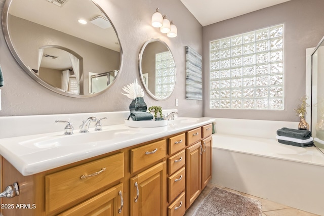 bathroom featuring visible vents, a garden tub, double vanity, tile patterned floors, and a sink